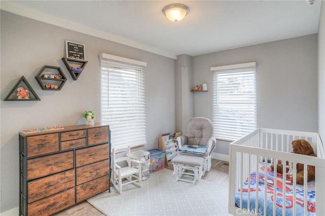 bedroom featuring a nursery area and light hardwood / wood-style floors