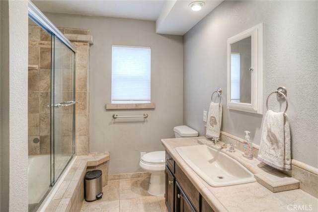 bathroom with a shower with door, vanity, tile patterned flooring, and toilet