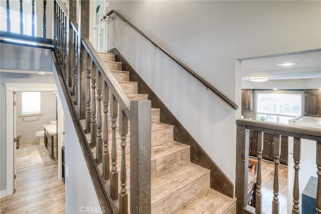 stairs featuring a wealth of natural light and wood-type flooring