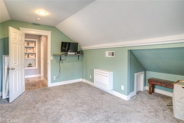 additional living space with lofted ceiling, light carpet, and built in shelves