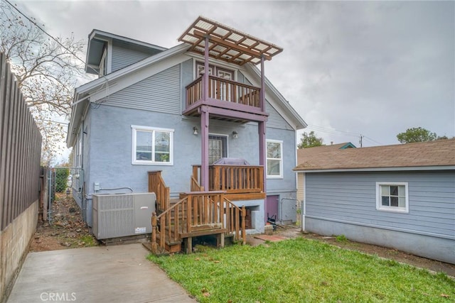 back of property with a balcony, a yard, and central AC unit