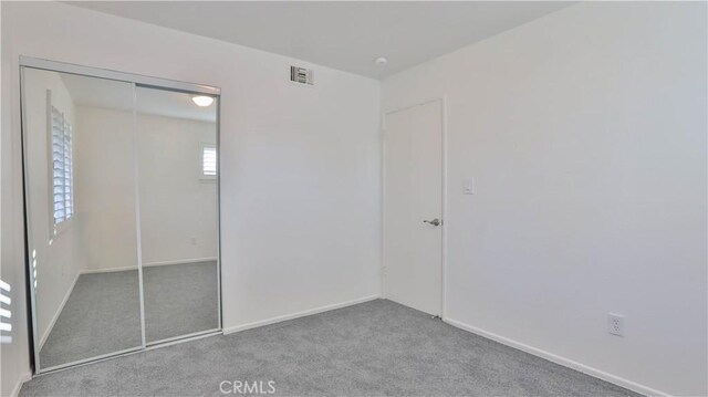 unfurnished bedroom featuring light colored carpet and a closet