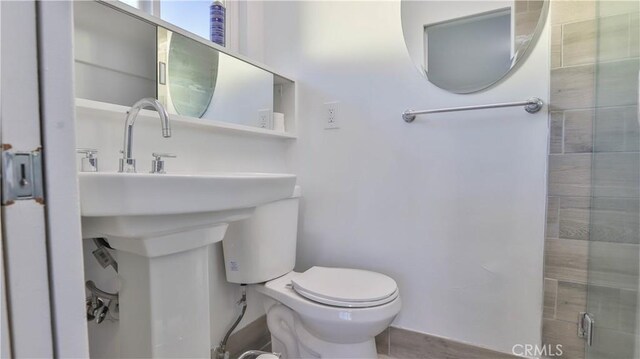 bathroom featuring a shower with door and toilet