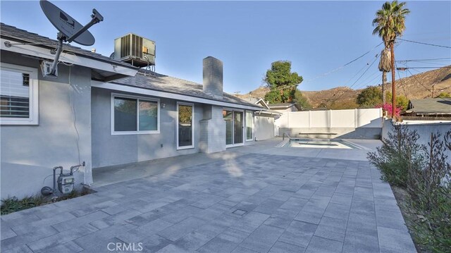 rear view of house featuring central AC unit and a patio area