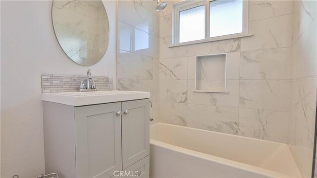 bathroom featuring tiled shower / bath, vanity, and backsplash