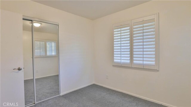 unfurnished bedroom with a closet and dark colored carpet