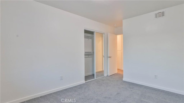 unfurnished bedroom with light colored carpet and a closet