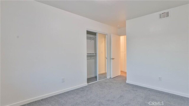 unfurnished bedroom featuring light colored carpet and a closet