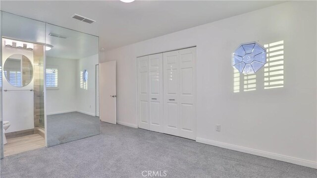 unfurnished bedroom featuring light carpet and a closet