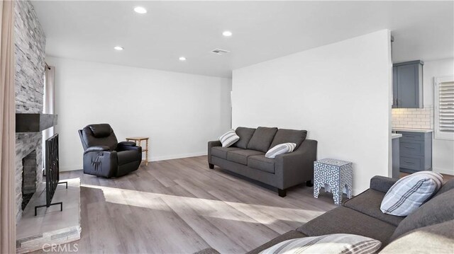 living room with a stone fireplace and light hardwood / wood-style flooring