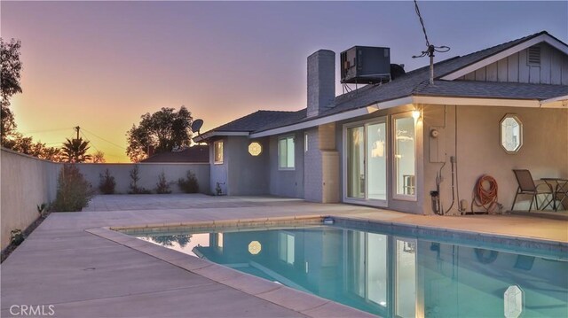 pool at dusk featuring a patio area