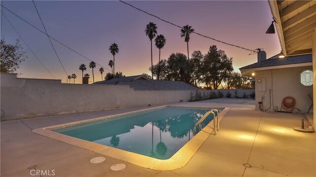 pool at dusk featuring a patio