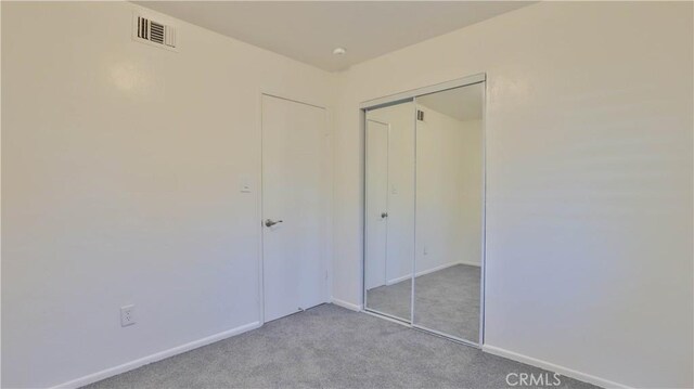 unfurnished bedroom with light carpet and a closet