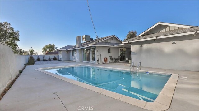 view of swimming pool with central air condition unit and a patio