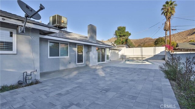 back of house featuring a swimming pool, a patio area, and central air condition unit