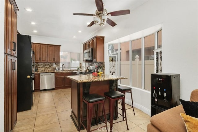 kitchen featuring decorative backsplash, a breakfast bar, stainless steel appliances, and light stone counters