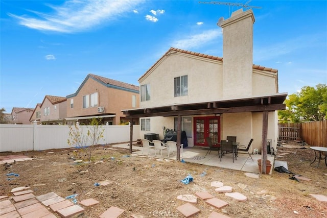 rear view of property featuring french doors, cooling unit, and a patio area