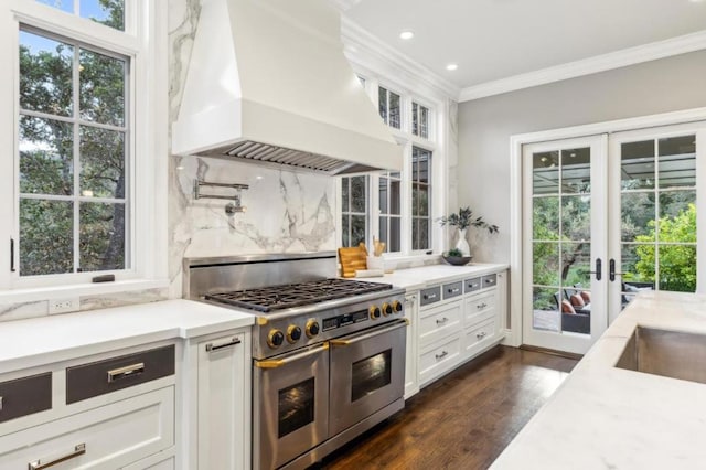 kitchen with white cabinets, ornamental molding, range with two ovens, and premium range hood