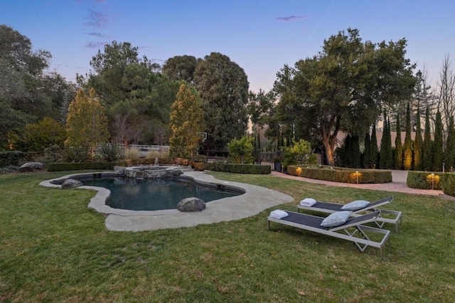 pool at dusk featuring a yard