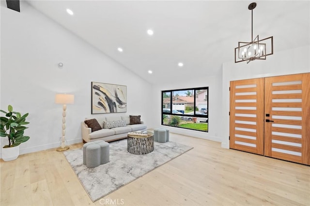 living room with an inviting chandelier, light hardwood / wood-style floors, and high vaulted ceiling