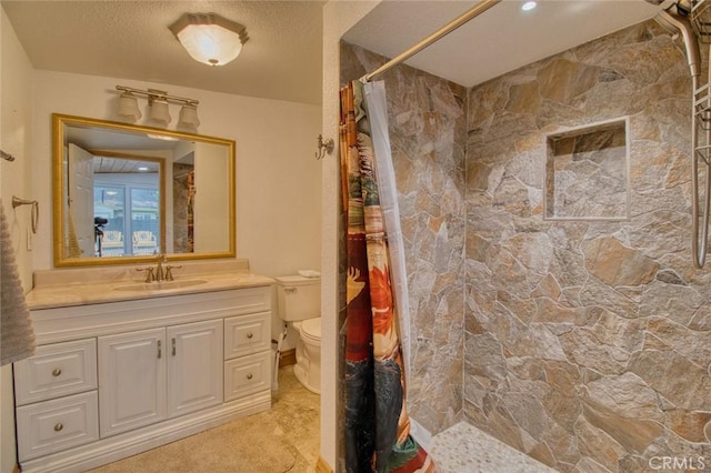 bathroom featuring vanity, a textured ceiling, toilet, and walk in shower