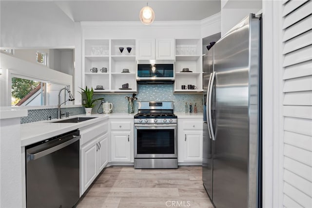 kitchen featuring appliances with stainless steel finishes, light wood-type flooring, backsplash, sink, and white cabinets