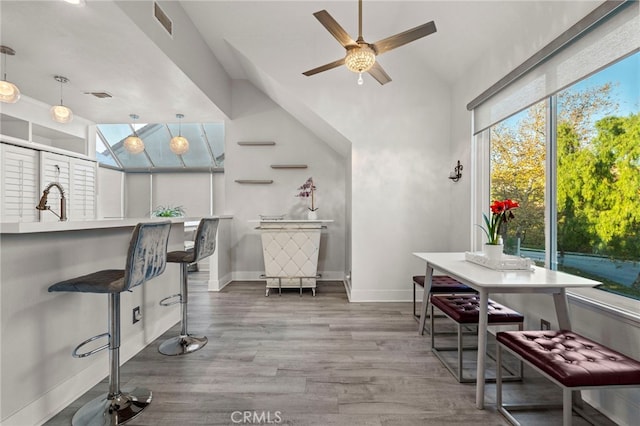 interior space with ceiling fan, sink, high vaulted ceiling, pendant lighting, and hardwood / wood-style flooring