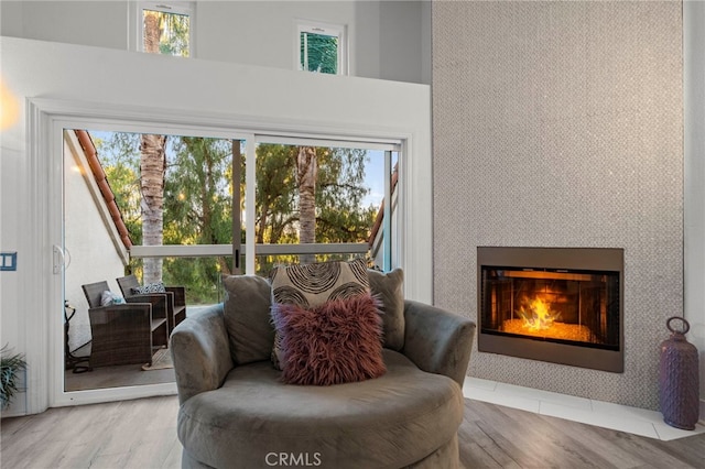 sitting room featuring wood-type flooring, a large fireplace, and a wealth of natural light