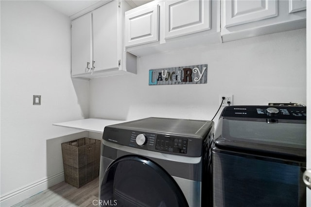 laundry room with cabinets, light hardwood / wood-style floors, and washer and clothes dryer