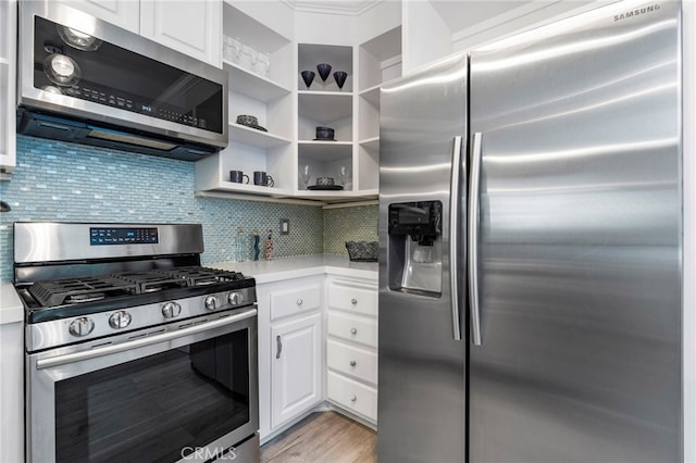 kitchen with tasteful backsplash, white cabinetry, light hardwood / wood-style flooring, and stainless steel appliances