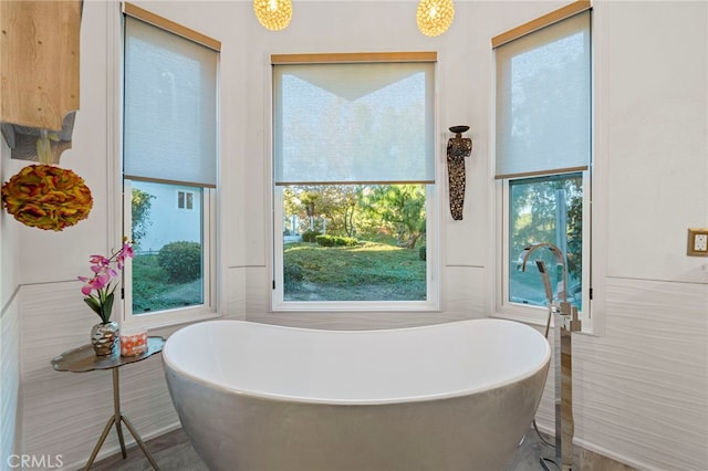 bathroom with plenty of natural light, a tub, and tile walls