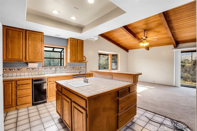 kitchen with a healthy amount of sunlight, tile counters, an island with sink, and light colored carpet