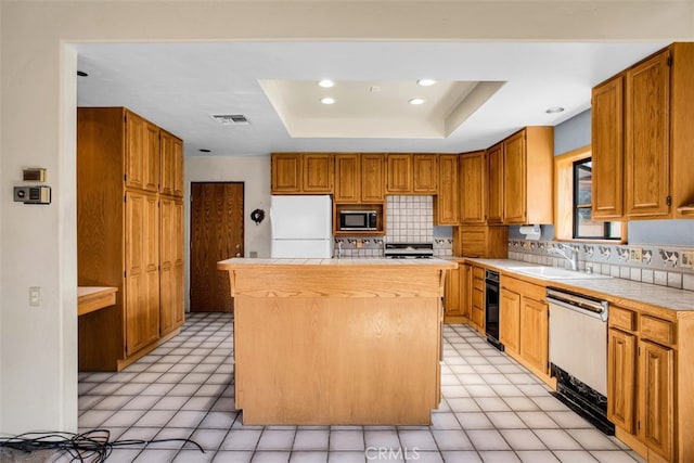 kitchen with a center island, sink, stainless steel appliances, a raised ceiling, and decorative backsplash