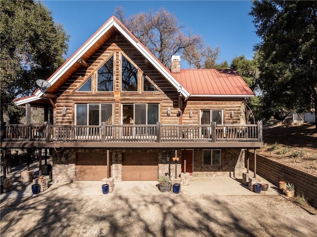 view of front facade with metal roof, stone siding, a deck, and a chimney