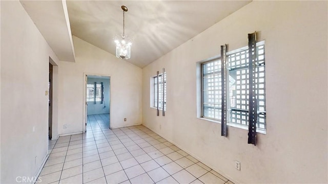 spare room featuring a notable chandelier, a healthy amount of sunlight, light tile patterned flooring, and lofted ceiling