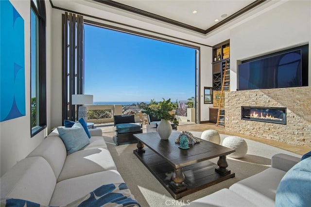 living room featuring a stone fireplace, a wealth of natural light, and ornamental molding