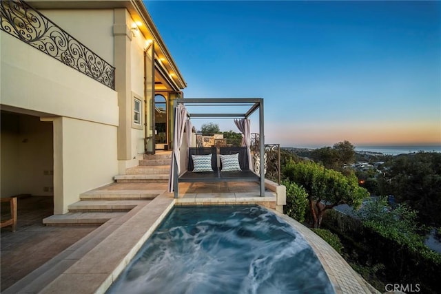 pool at dusk with a hot tub