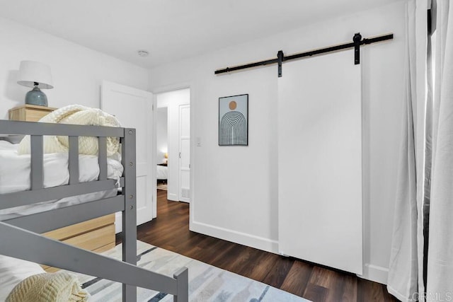 bedroom with dark hardwood / wood-style flooring and a barn door