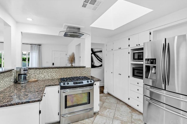 kitchen with dark stone counters, white cabinetry, appliances with stainless steel finishes, and tasteful backsplash