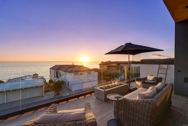 patio terrace at dusk with a water view and an outdoor living space with a fire pit