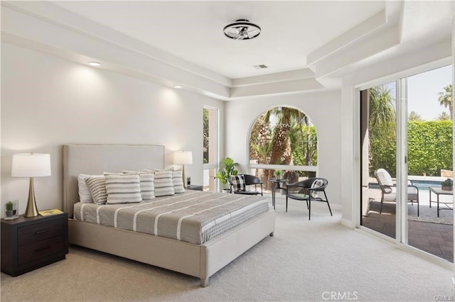 bedroom featuring a tray ceiling, light colored carpet, and access to exterior