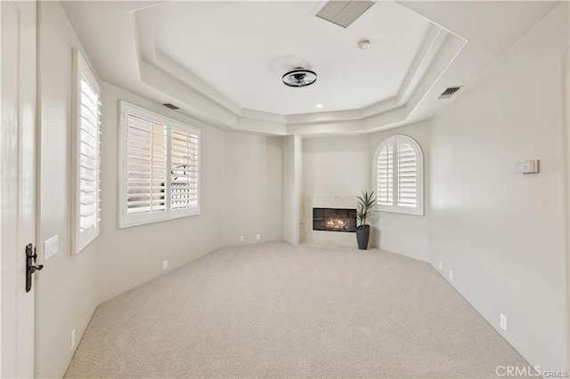 unfurnished living room featuring a tray ceiling and carpet flooring