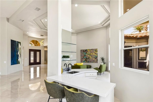 interior space with kitchen peninsula, french doors, a breakfast bar area, and sink