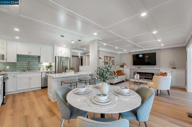 dining space featuring crown molding, sink, and light wood-type flooring