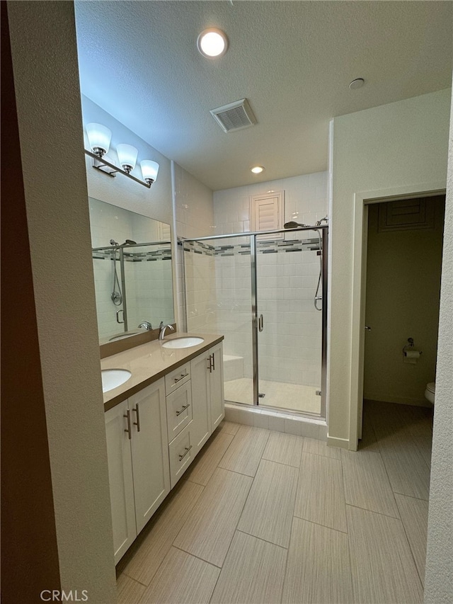 bathroom featuring a textured ceiling, vanity, toilet, and walk in shower