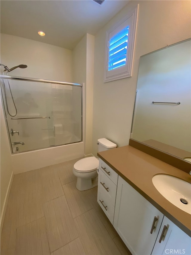 full bathroom featuring vanity, bath / shower combo with glass door, and toilet