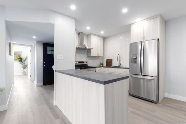 kitchen with decorative backsplash, sink, light hardwood / wood-style flooring, appliances with stainless steel finishes, and wall chimney exhaust hood