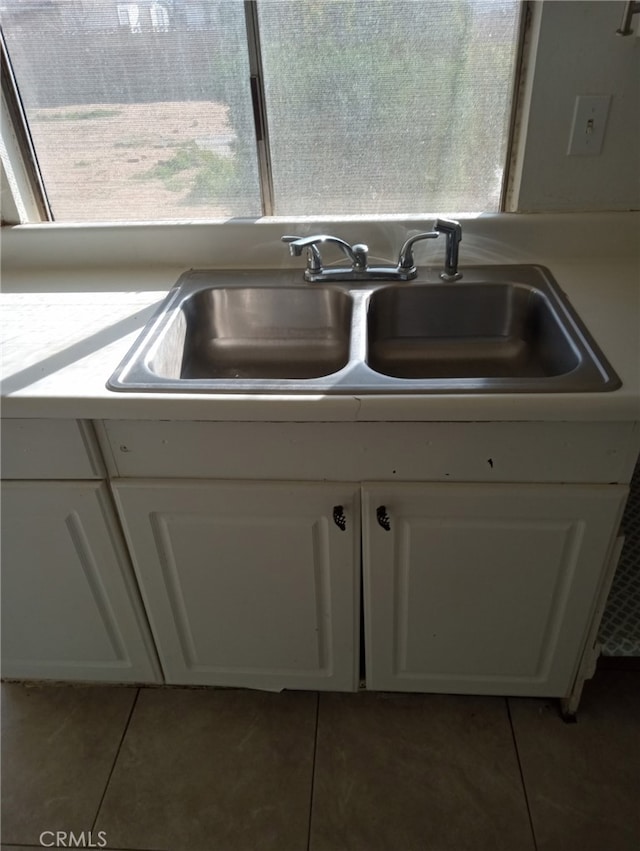 interior details with white cabinetry, light countertops, and a sink