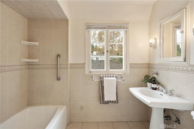 bathroom with tile walls, a bath, and tile patterned floors