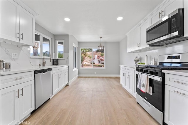 kitchen with backsplash, hanging light fixtures, light hardwood / wood-style flooring, white cabinetry, and stainless steel appliances